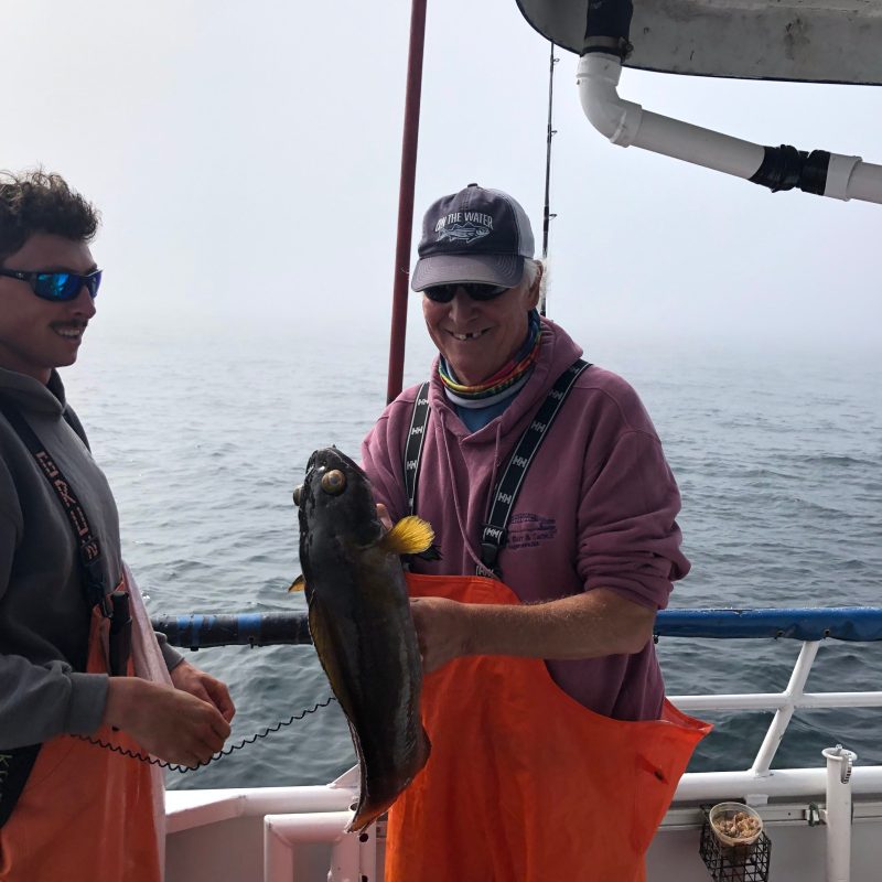 a person holding a fish on a boat in a body of water
