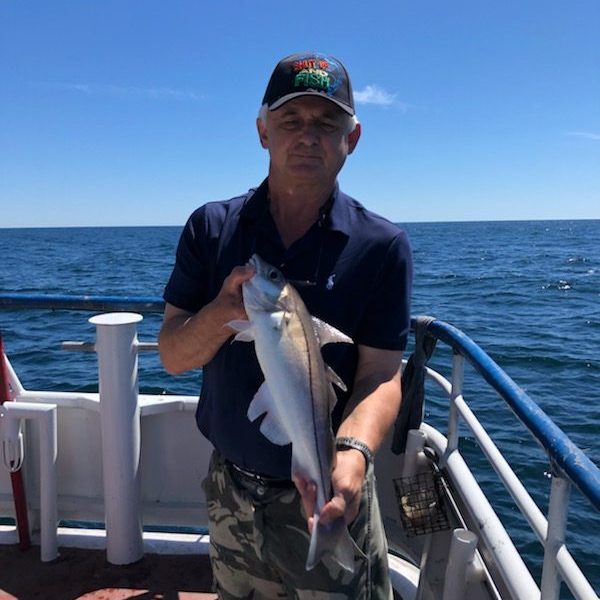 a man holding a fish on a boat in a body of water