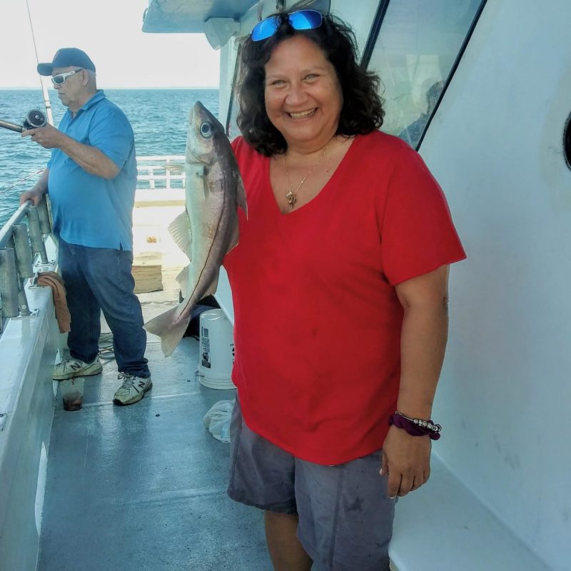 a person holding a fish on a boat posing for the camera