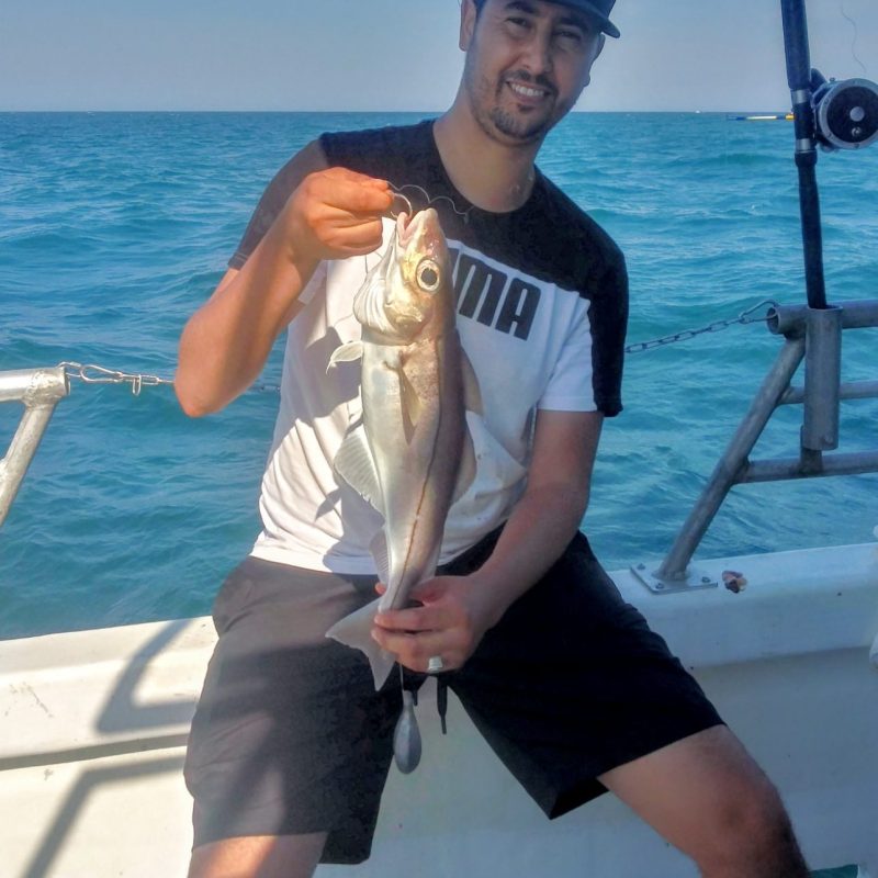 a person holding a fish on a boat in a body of water