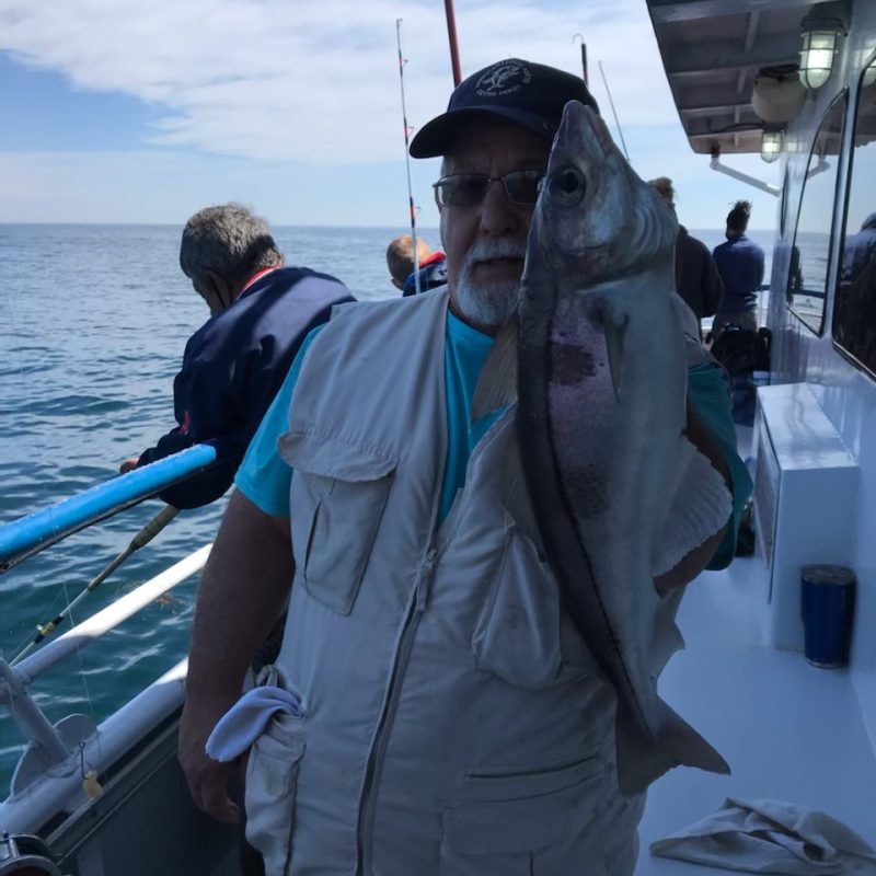 a man holding a fish on a boat