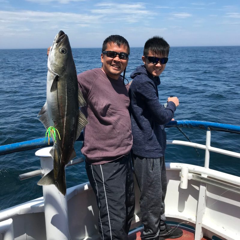 a man holding a fish on a boat in a body of water