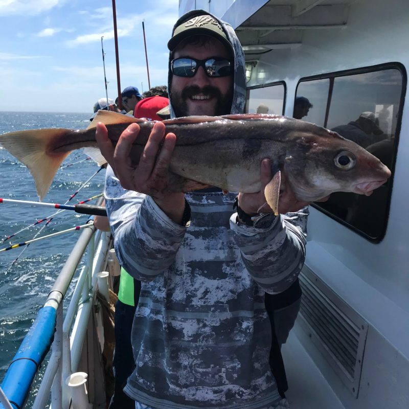 a man holding a fish on a boat