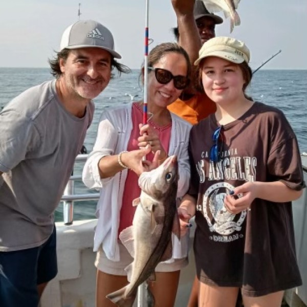 a group of people standing next to a fish in the water