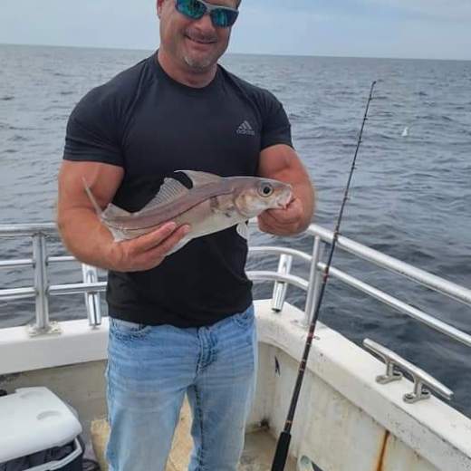 a man holding a fish on a boat in a body of water