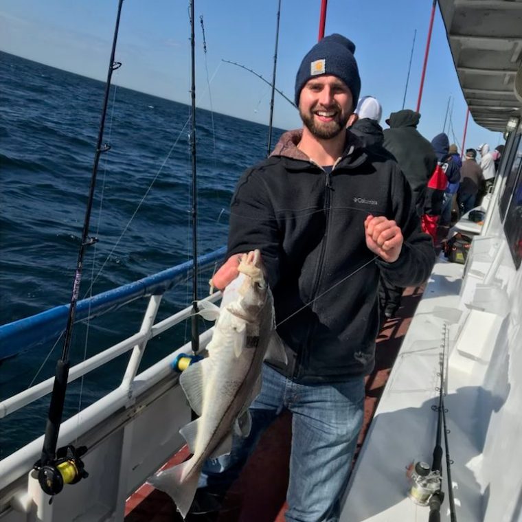 a man holding a fish on a boat posing for the camera