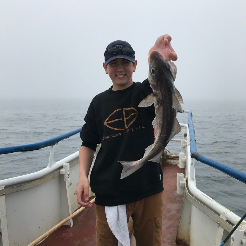 a person holding a fish on a boat in a body of water