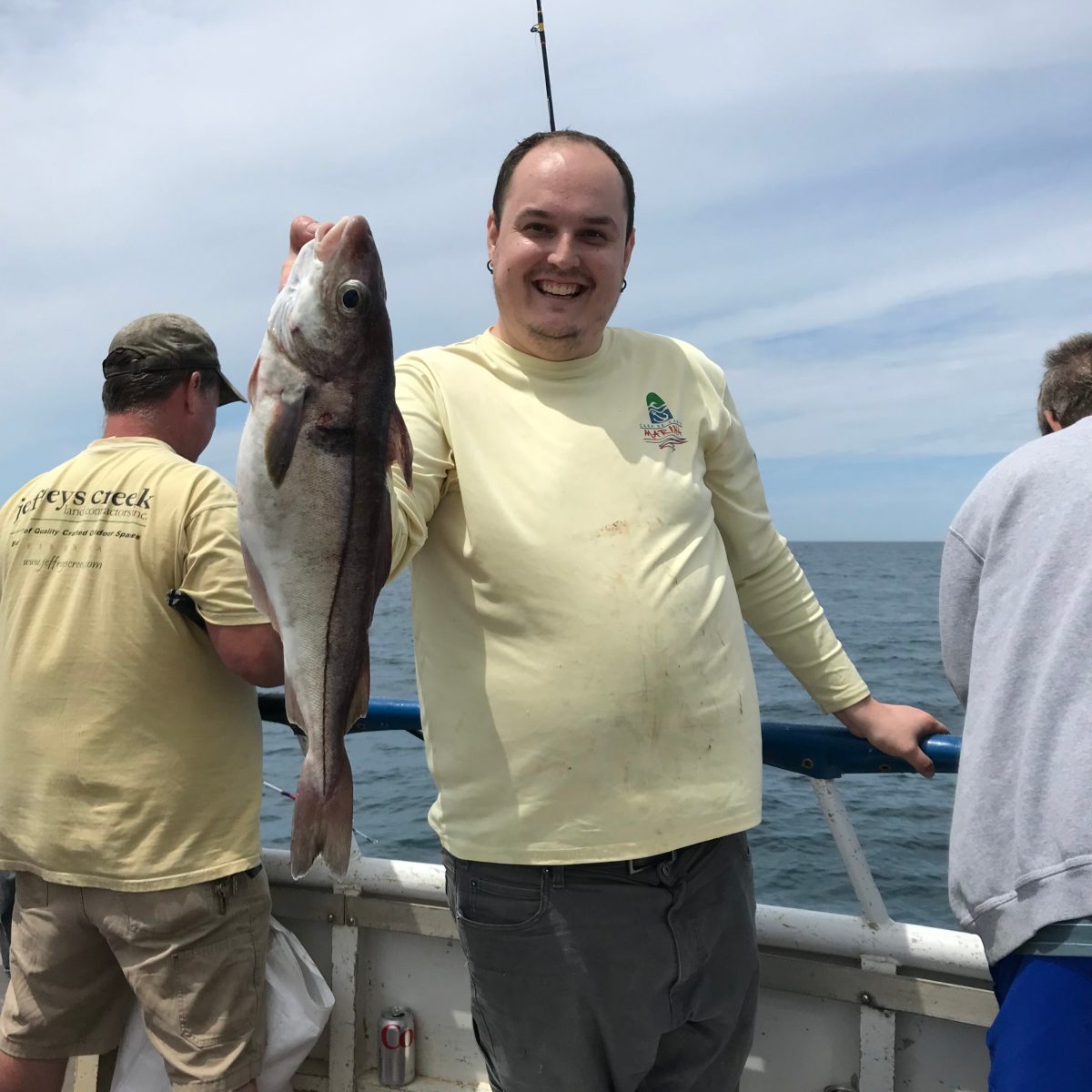 a group of people standing next to a person holding a fish