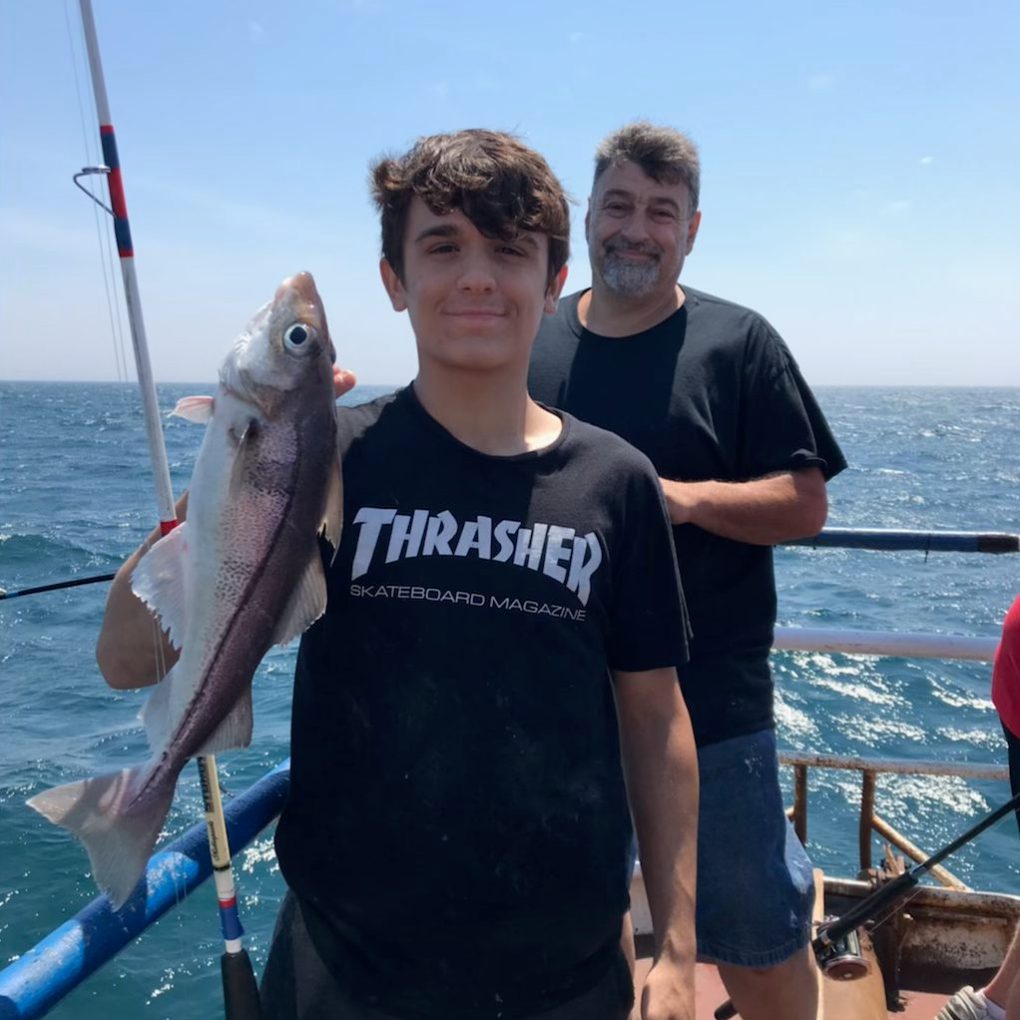 a man holding a fish on a boat in a body of water