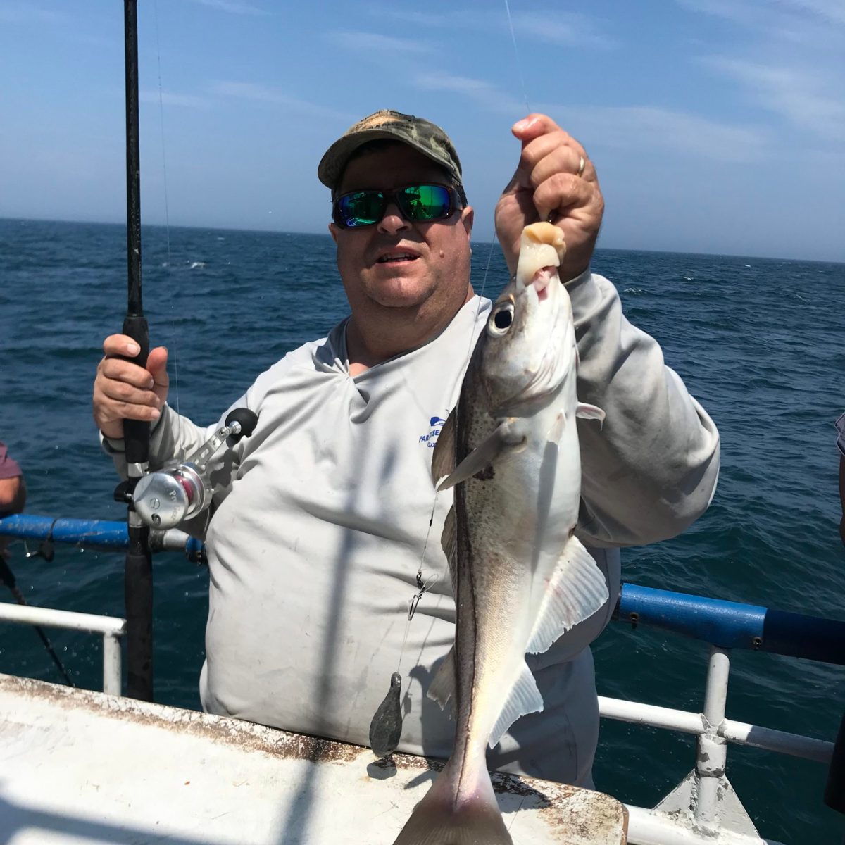 a man holding a fish on a boat in a body of water