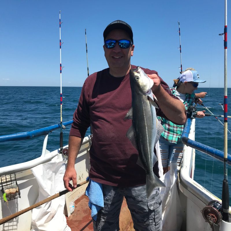 a man holding a fish on a boat in a body of water