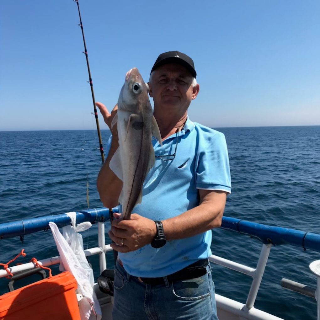 a person holding a fish on a boat in a body of water