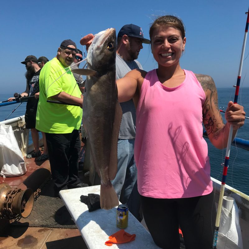 a group of people standing next to a person holding a fish