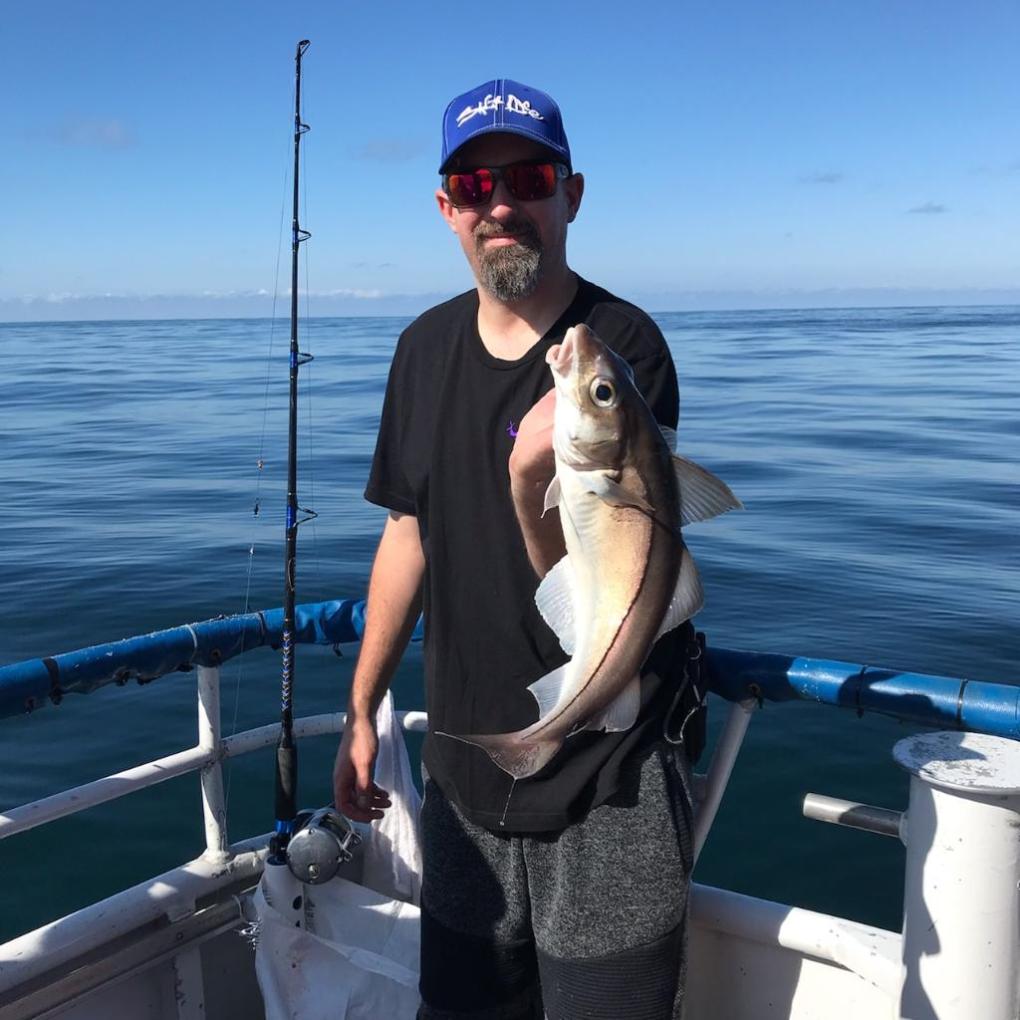 a person holding a fish on a boat in a body of water