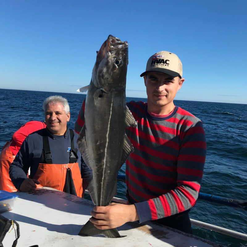 a man and woman sitting next to a body of water