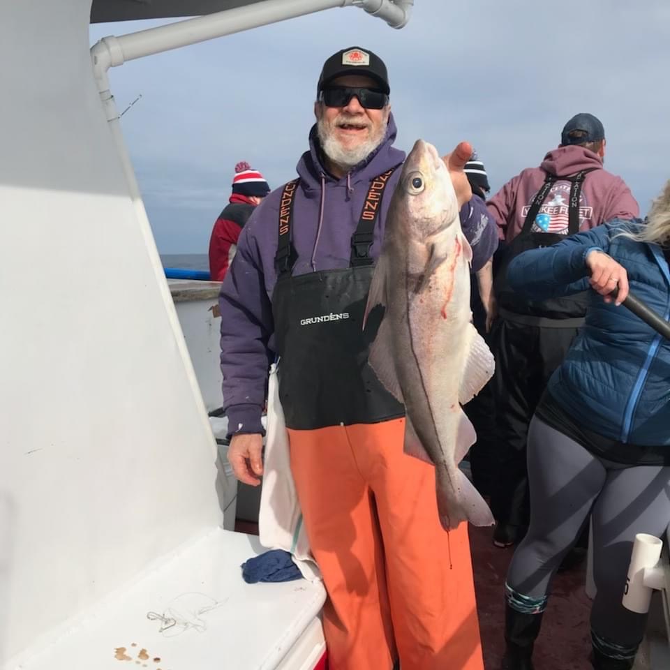 a group of people standing next to a person holding a fish