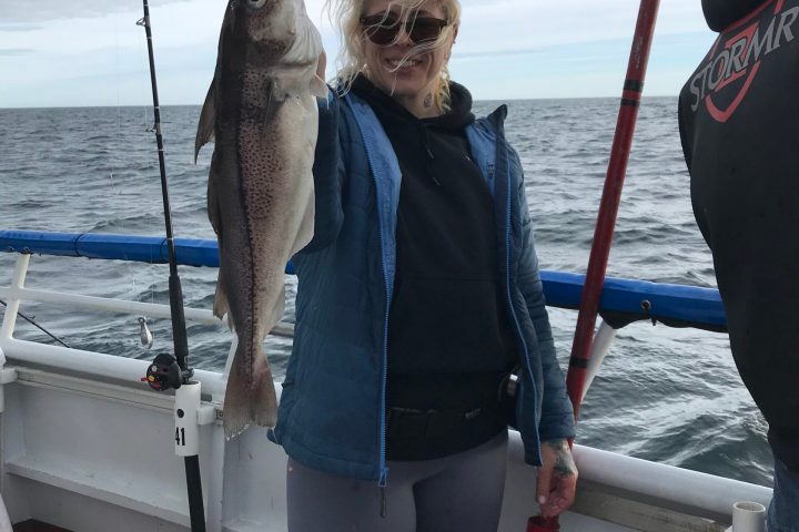 a person holding a fish on a boat in a body of water