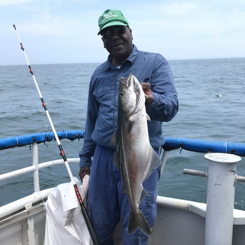 a person holding a fish on a boat in a body of water
