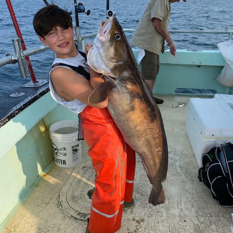 a man holding a fish on a boat in the water