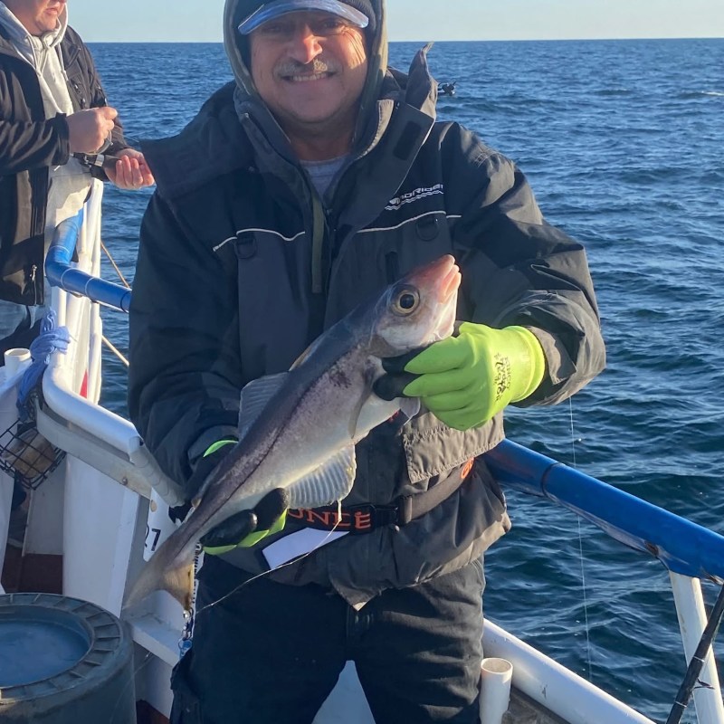 a man holding a fish on a boat in a body of water