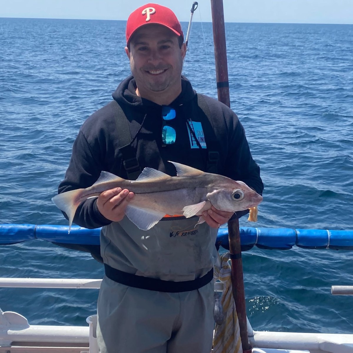 a man holding a fish on a boat in a body of water