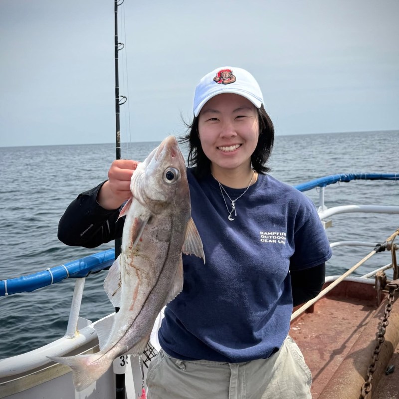 a person holding a fish on a boat in a body of water
