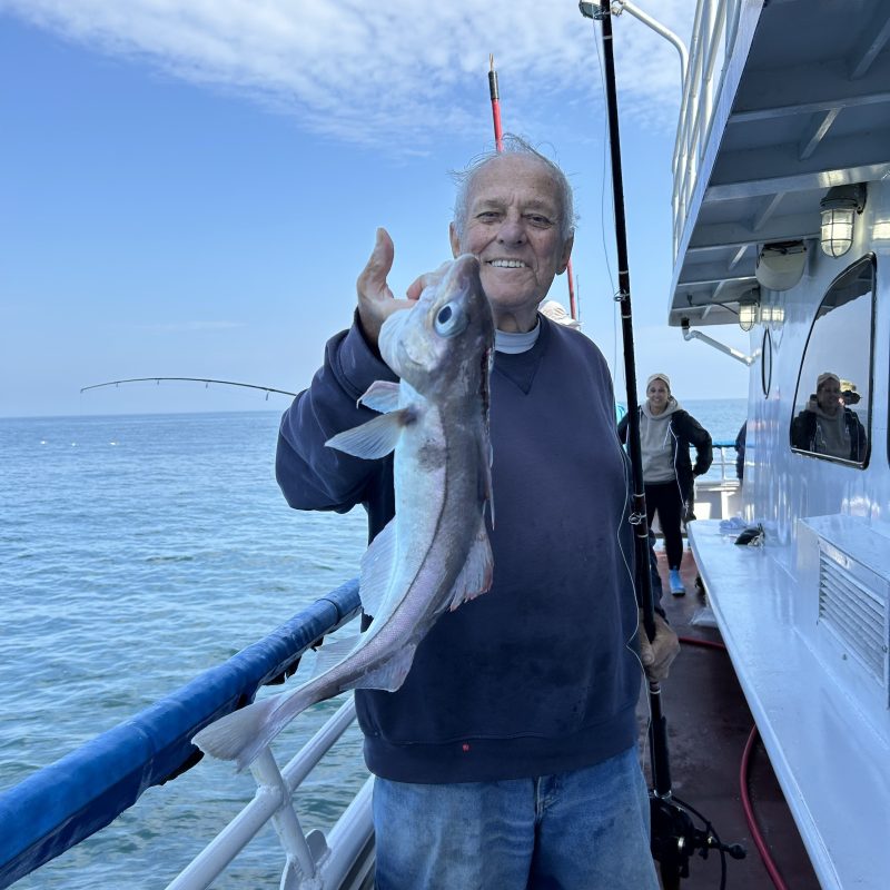 a person holding a fish on a boat in a body of water