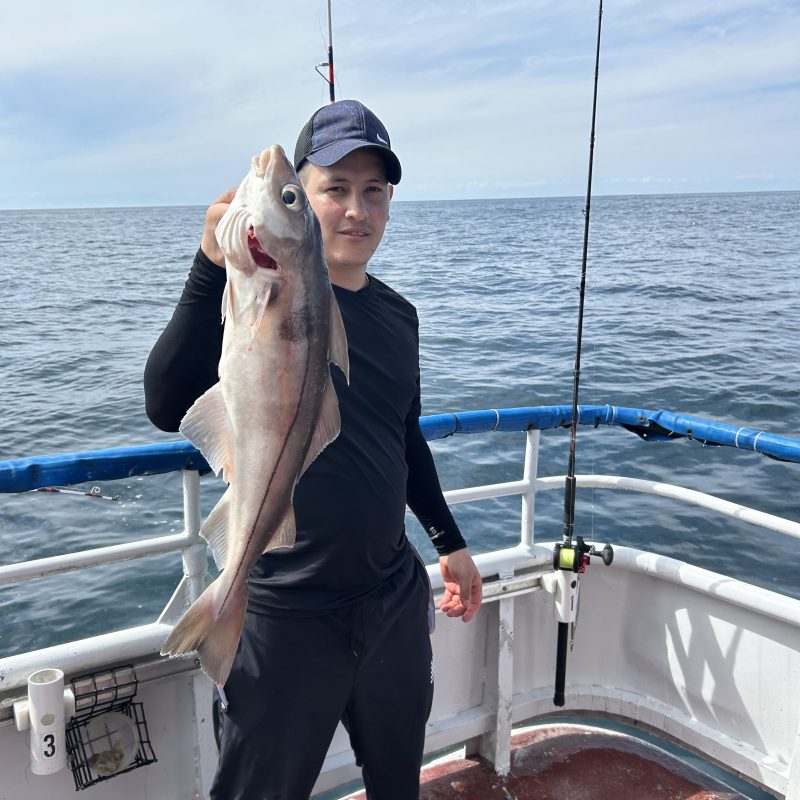 Person on a boat holding a large fish with the ocean in the background.