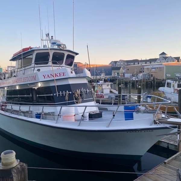 Large fishing boat docked at a harbor during sunset.