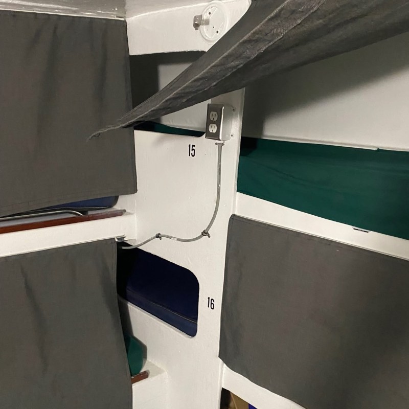Interior of a boat with curtained storage areas and a wall cable conduit.