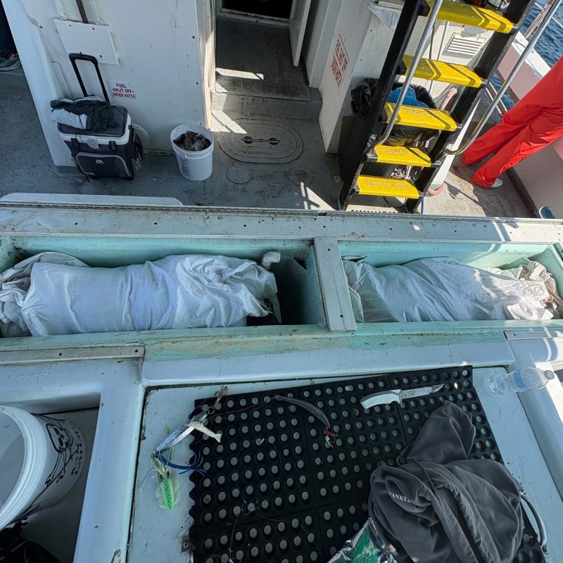Fishing boat deck with storage compartments and equipment.