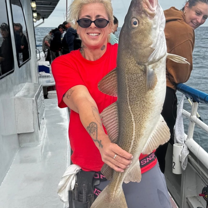 Person holding a large fish on a boat deck.