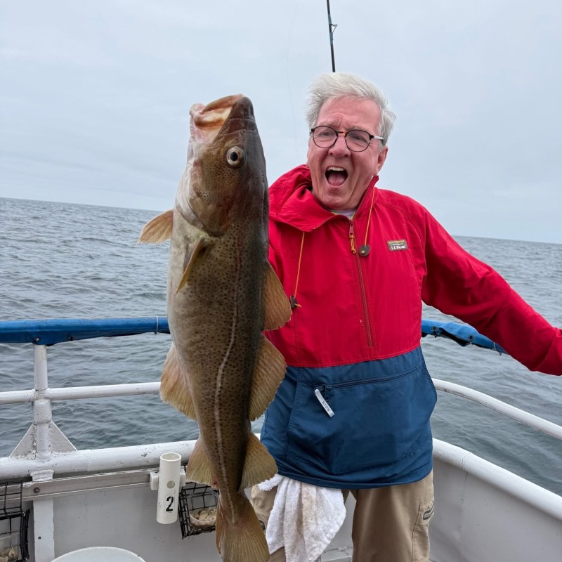 Person excitedly holding a large fish on a boat at sea.